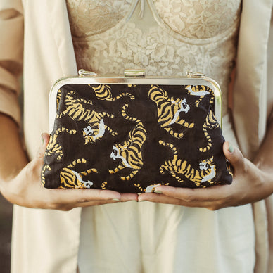 This clutch is our exclusive collection to shine the light to Indonesia's Sumatran tiger, one of the world's critically endangered animals. According to WWF, there are only fewer than 400 Sumatran tigers left and if deforestation poaching action continues, Sumatran tiger could be the first large carnivore animal to go extinct in the 21st century. 
Indonesia already has lost two tiger subspecies, the Bali and Javan tigers, which became extinct in the 1940s and 1980s respectively. Three of the world's eight tiger subspecies have gone extinct in the past 70 years; the remaining five subspecies are all endangered. 

WWF supports anti-poaching patrols in Indonesia and has helped arrest and prosecute poachers. WWF is also investing in habitat conservation and a biological assessment of tigers in the lowlands of central Sumatra to better address threats to the remaining population. 
How we can help: Share this story, switch to sustainable products to protect our forests, donate to organizations that support anti-poaching actions to protect Sumatran tigers. Take action here: 
International Tiger Project https://www.internationaltigerproject.org/donate/ 
WWF Indonesia - Sahabat Harimau https://www.wwf.or.id/cara_anda_membantu/bertindak_sekarang_juga/sahabatharimau/ 
Fauna Flora International https://www.fauna-flora.org/species/sumatran-tiger 
We hope through this Sumatran tiger clutch, we can help share the story to raise awareness of this critical condition, and inspire people to take action. 
Sumatran Tiger Clutch detail: • Dimension: 8.75" W x 6.2 H x 2.75 D • Strap drop: 11.75 inches • Composition: 100% Linen fabric, Cotton Embroidery, Gold metal chain strap 
*** We will donate the proceeds from each Sumatran tiger clutch purchased directly from our website to one of the organizations listed above. 
Ships separately from our friends at BrunnaCo 