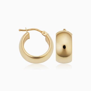 Radiant. Bold. Timeless. Our High Society Hoops are a must-have for every fine jewelry collection. The wide, flattened solid gold tubes give them a classic, vintage feel, while the curved design creates a dome effect for maximum shine. 
The Finer Points: 

Metal: 14 Karat Yellow Gold
Dimensions: 7mm Width, 10mm Diameter
Hollow Construction
Latch Closure
Weight: 2 Grams

Ships separately from our friends at Oradina 
