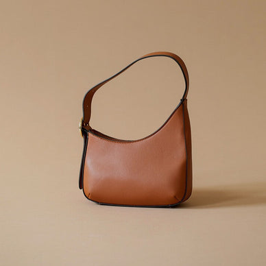 Asymmetrical shoulder bag with side buckle detail. Zipper entrance. Contrast edge paint detail. 
DIMENSIONS: 8.75IN LONG 9IN HEIGHT 2.5IN DEPTH 
Fulfilled by our friends at Kayla + Ava 

Please Note: Rewards cannot be applied to this product 
